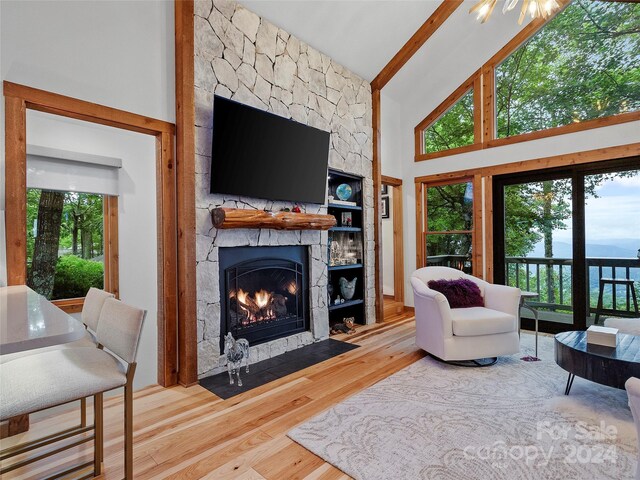 living room featuring hardwood / wood-style floors, high vaulted ceiling, a fireplace, and beamed ceiling