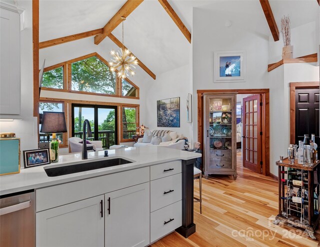 kitchen with high vaulted ceiling, sink, beam ceiling, stainless steel dishwasher, and light hardwood / wood-style flooring