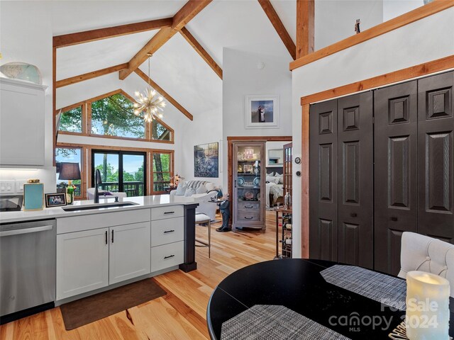 kitchen featuring light hardwood / wood-style flooring, white cabinets, high vaulted ceiling, stainless steel dishwasher, and sink