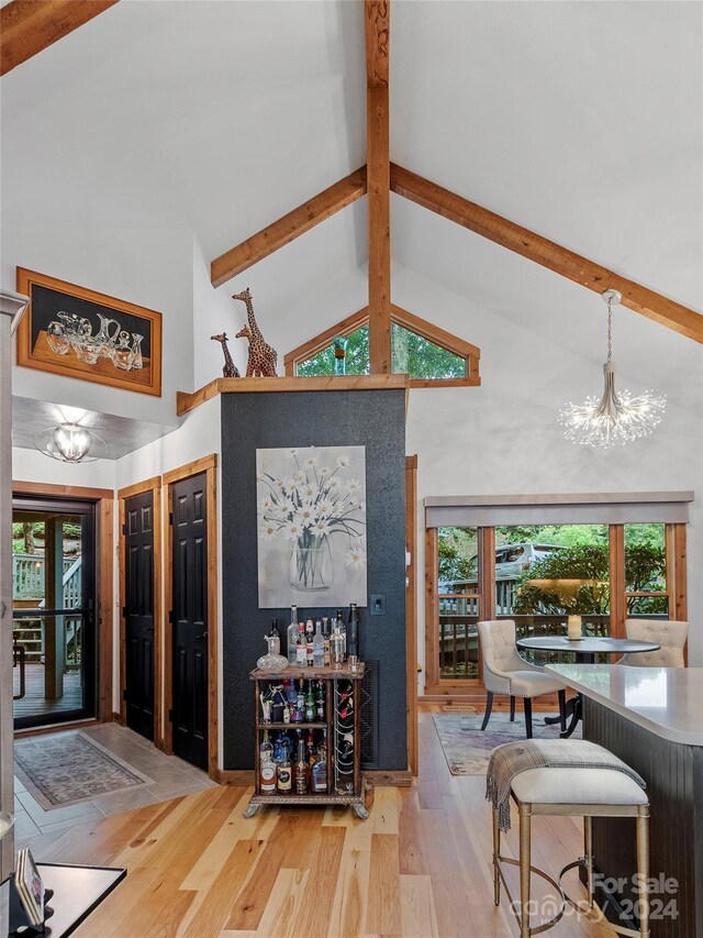 living room featuring beam ceiling, high vaulted ceiling, light hardwood / wood-style flooring, and a notable chandelier