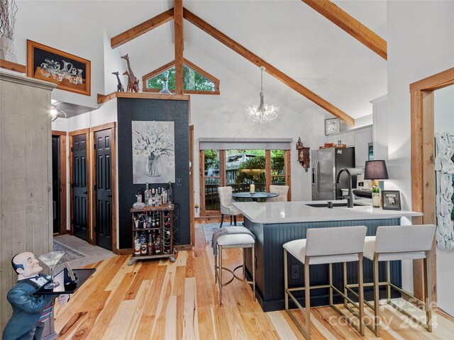 kitchen with high vaulted ceiling, stainless steel refrigerator with ice dispenser, beamed ceiling, and light hardwood / wood-style floors