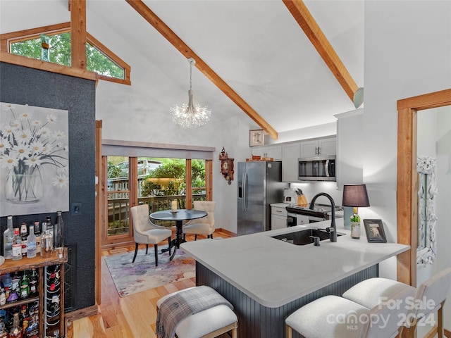 kitchen with high vaulted ceiling, appliances with stainless steel finishes, light wood-type flooring, beam ceiling, and a kitchen bar