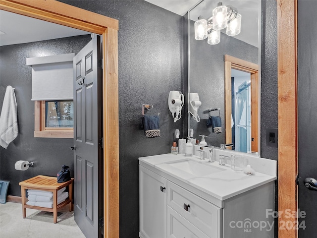 bathroom featuring tile patterned flooring, a textured wall, and vanity