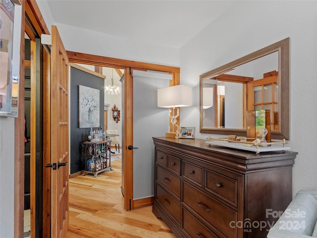 hall featuring light wood-type flooring and an inviting chandelier