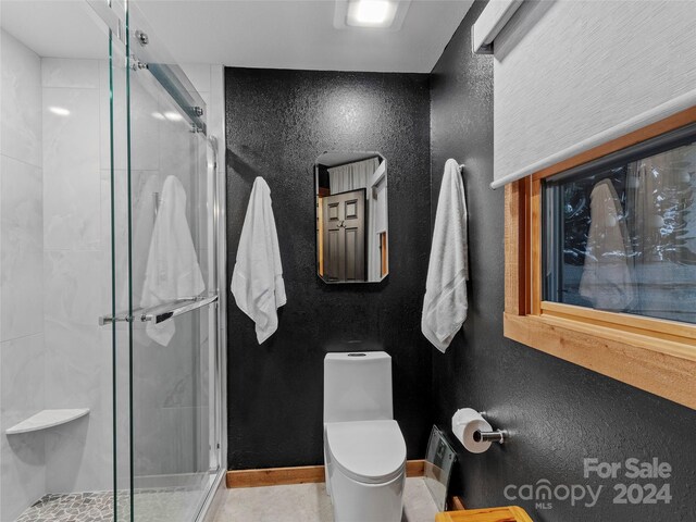 bathroom featuring tile patterned floors, a shower with door, and toilet