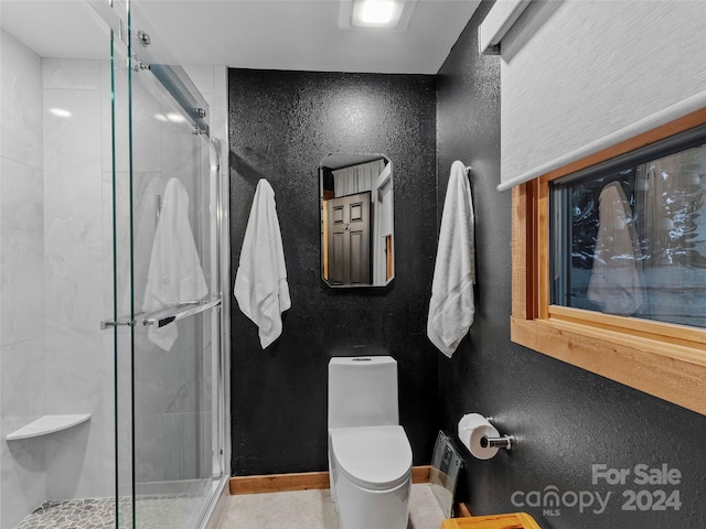 full bath featuring a textured wall, a stall shower, toilet, and baseboards