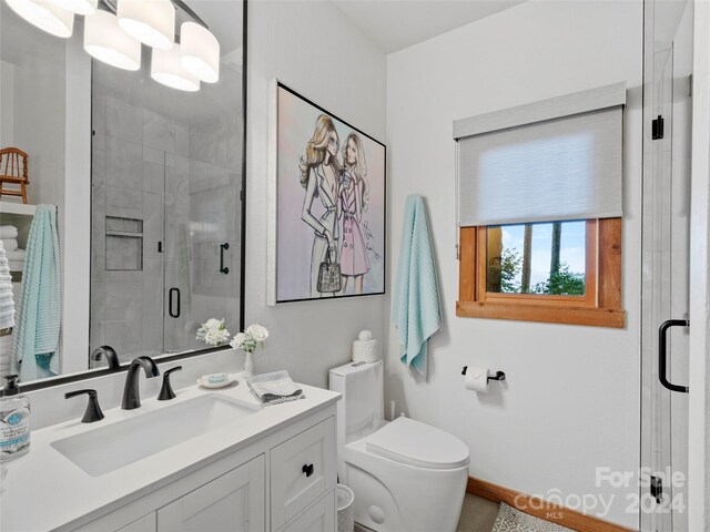 bathroom featuring a shower with door, toilet, and vanity