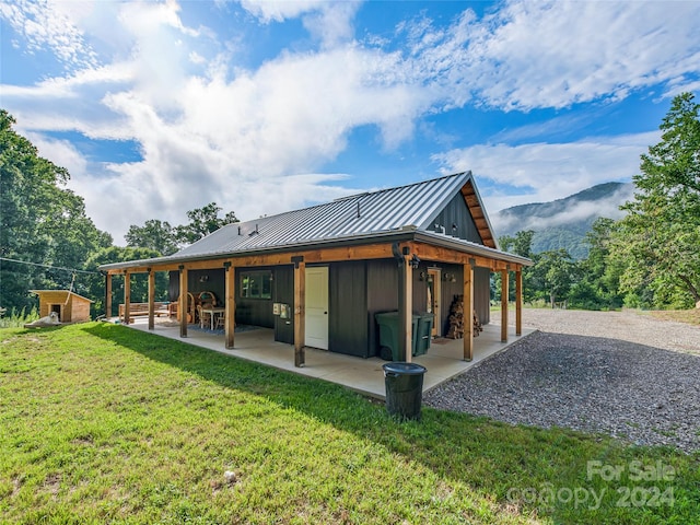 back of property featuring an outbuilding, a patio area, and a lawn