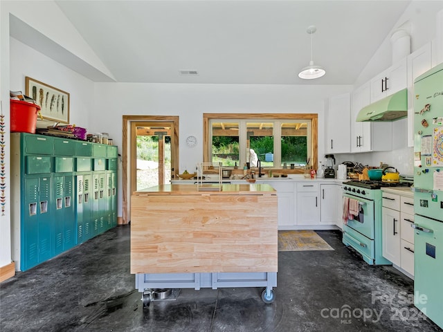 kitchen featuring gas range oven, pendant lighting, lofted ceiling, white cabinetry, and white fridge