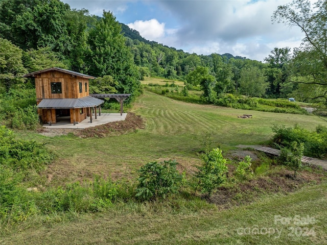 view of yard featuring a rural view, an outbuilding, and a pergola