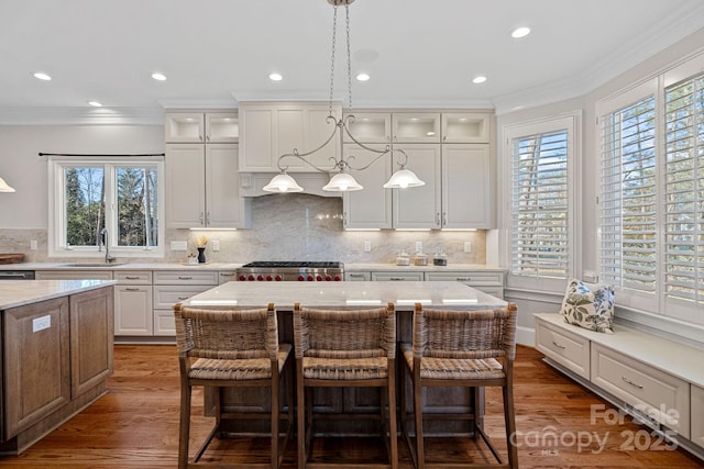 kitchen featuring white cabinetry, stove, a center island, and ornamental molding