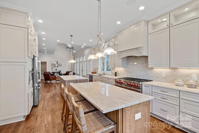 kitchen with high end stainless steel range, sink, white cabinetry, a center island, and pendant lighting