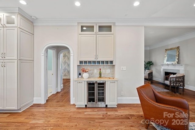 bar with white cabinetry, beverage cooler, light hardwood / wood-style floors, and backsplash