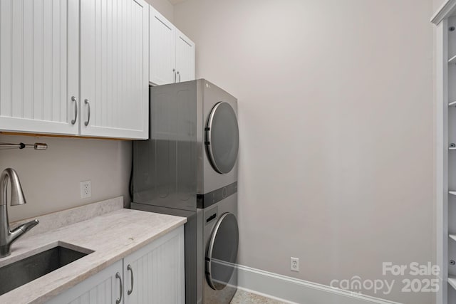 clothes washing area with cabinets, stacked washer and clothes dryer, and sink