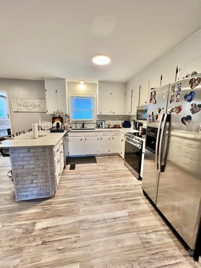 kitchen featuring white cabinetry, sink, light wood-type flooring, and appliances with stainless steel finishes