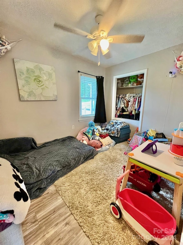 bedroom featuring hardwood / wood-style flooring, ceiling fan, a textured ceiling, and a closet