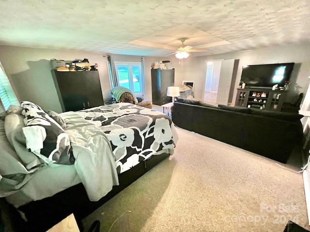 carpeted bedroom featuring ceiling fan and a textured ceiling