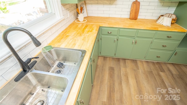 kitchen featuring backsplash, light hardwood / wood-style floors, green cabinets, and sink