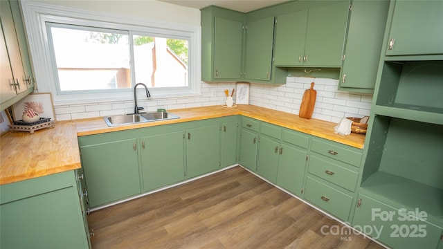 kitchen featuring backsplash, wood counters, sink, and green cabinetry