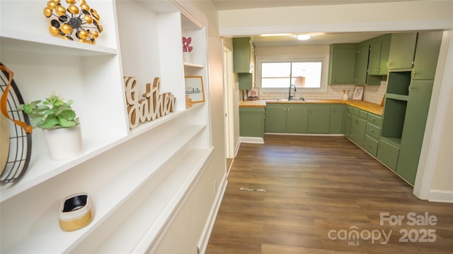 kitchen featuring dark hardwood / wood-style flooring, decorative backsplash, sink, and green cabinetry