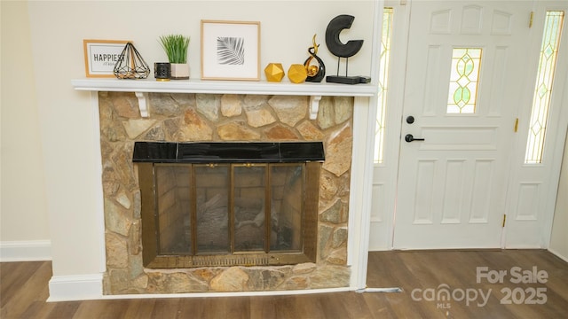 room details with hardwood / wood-style flooring and a stone fireplace