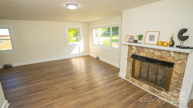 living room with a stone fireplace and hardwood / wood-style flooring