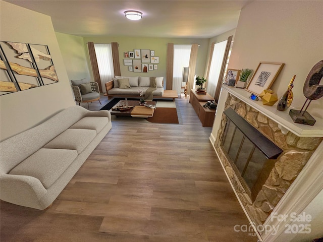 living room featuring a stone fireplace, a healthy amount of sunlight, and wood-type flooring