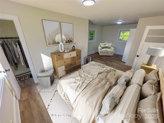 bedroom featuring a walk in closet, dark wood-type flooring, and a closet