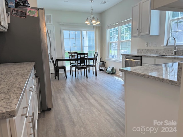 kitchen with white cabinetry, sink, light wood-type flooring, and an inviting chandelier