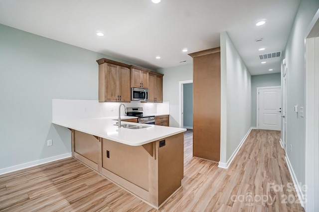 kitchen featuring kitchen peninsula, sink, light hardwood / wood-style flooring, and stainless steel appliances