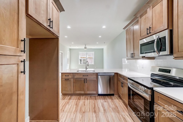 kitchen with decorative backsplash, sink, light wood-type flooring, kitchen peninsula, and stainless steel appliances