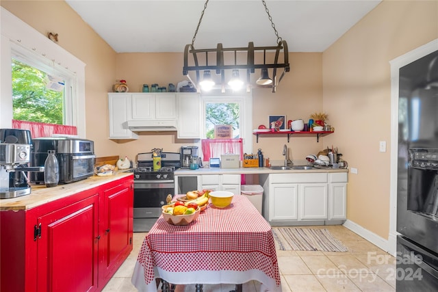 kitchen featuring stainless steel gas range, sink, light tile patterned flooring, and white cabinetry