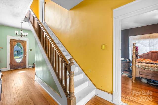 stairs with wood-type flooring and a chandelier