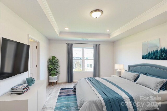 bedroom with a raised ceiling, light hardwood / wood-style flooring, and crown molding