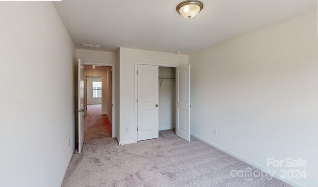 unfurnished bedroom featuring a closet and light colored carpet