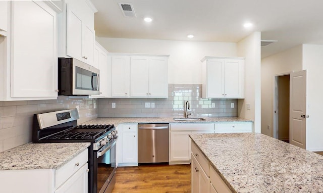 kitchen featuring white cabinetry, sink, light stone counters, and stainless steel appliances