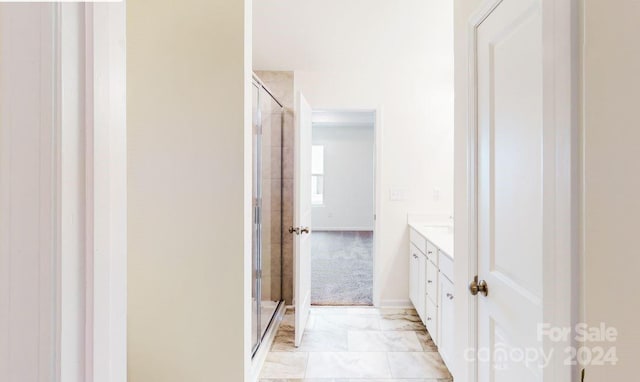 bathroom featuring a shower with door and vanity