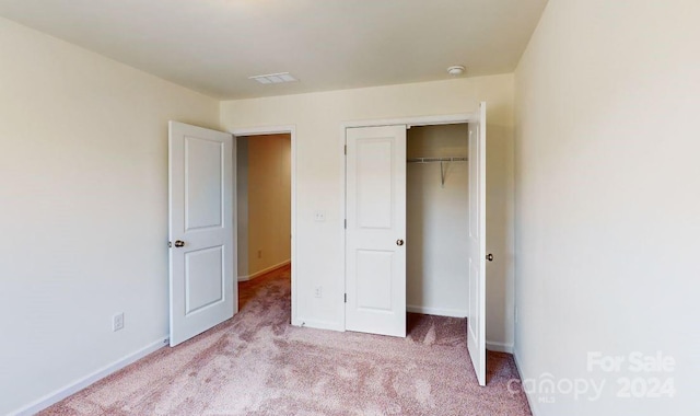 unfurnished bedroom featuring a closet and light carpet