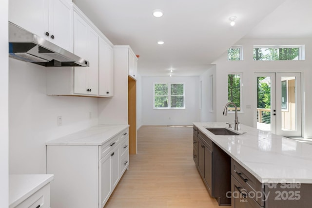 654 Hollybrook Dr, Flat Rock, NC 28731 - kitchen with under cabinet range hood, light wood-style flooring, light stone counters, white cabinets, and recessed lighting