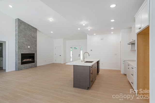 654 Hollybrook Dr, Flat Rock, NC 28731 - kitchen with a kitchen island with sink, light countertops, light wood-style floors, under cabinet range hood, and white cabinets