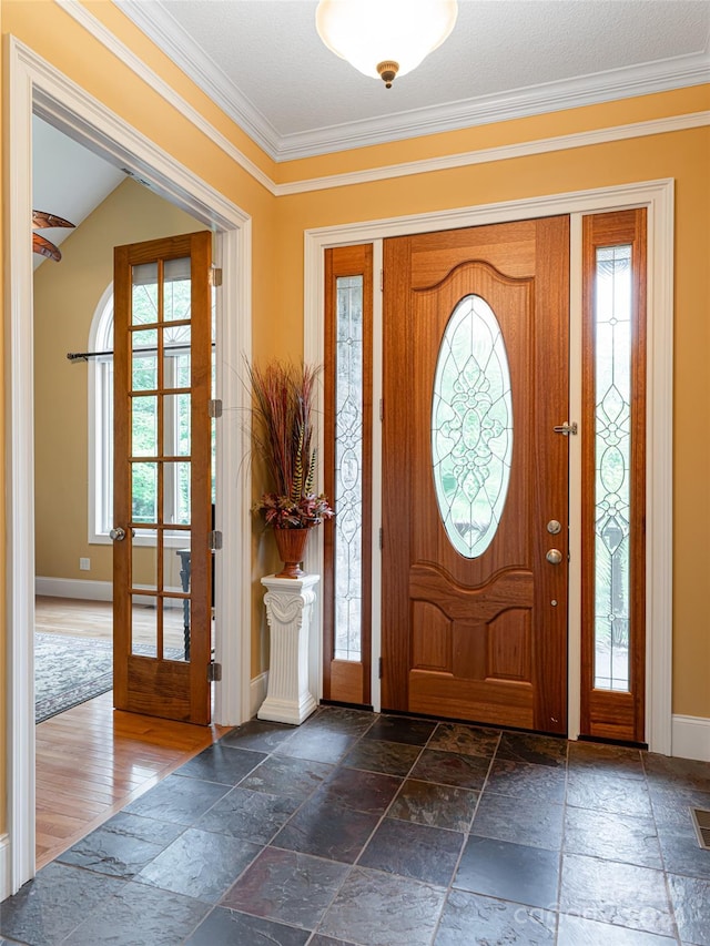 entrance foyer featuring a healthy amount of sunlight, crown molding, and dark tile patterned flooring