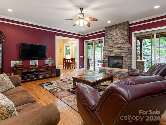 living room with light hardwood / wood-style flooring, a stone fireplace, plenty of natural light, and ceiling fan