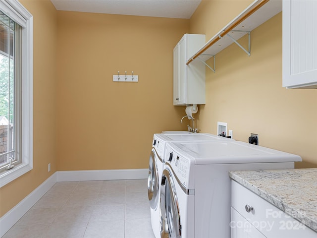 washroom with light tile patterned floors, washer and dryer, and cabinets