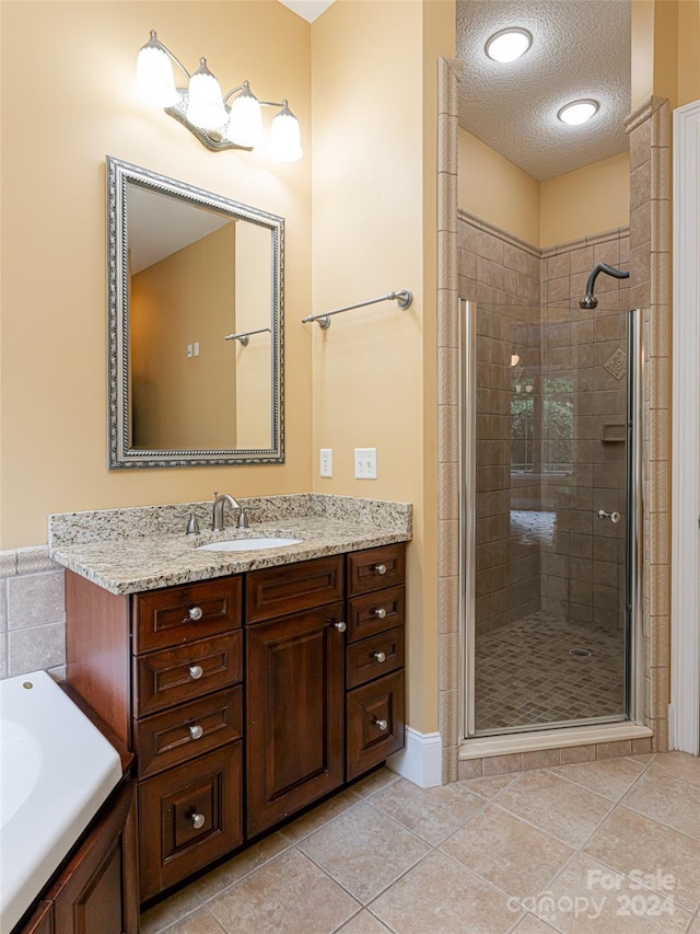 bathroom featuring tile patterned floors, vanity, separate shower and tub, and a textured ceiling