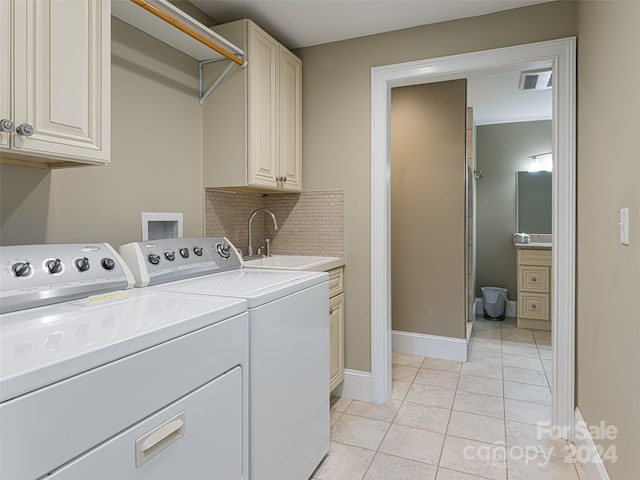 washroom featuring washing machine and clothes dryer, sink, light tile patterned flooring, and cabinets