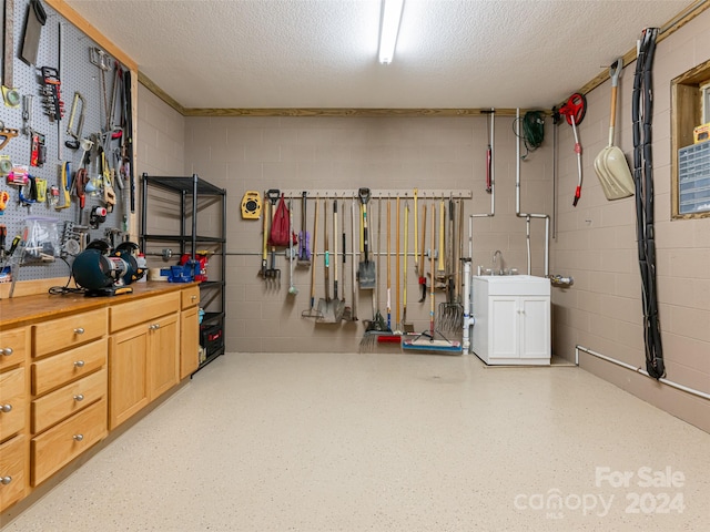 basement with a workshop area, sink, and a textured ceiling