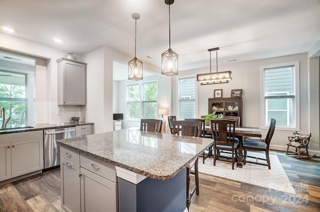 kitchen with sink, a center island, hanging light fixtures, gray cabinets, and dishwasher