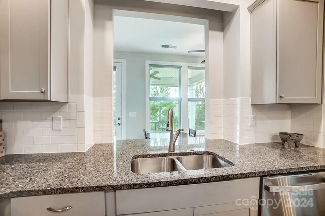 kitchen featuring dark stone counters, tasteful backsplash, sink, gray cabinets, and stainless steel dishwasher