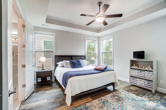 bedroom featuring ensuite bathroom, ceiling fan, dark hardwood / wood-style floors, and a tray ceiling