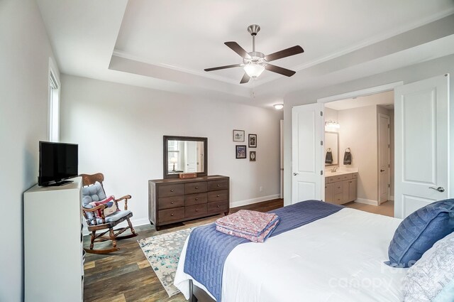 bedroom with ensuite bath, ceiling fan, hardwood / wood-style floors, and a tray ceiling